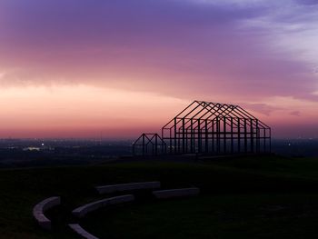 Built structure on field against sky at sunset