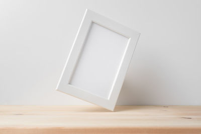 Close-up of white table on hardwood floor against wall