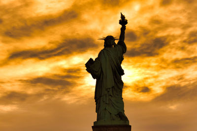 Low angle view of statue against cloudy sky during sunset