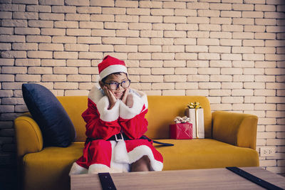 Woman sitting on sofa against wall at home