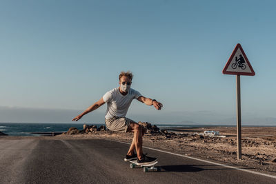 Full length of man skating on road against clear sky