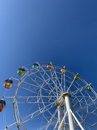 Low angle view of ferris wheel against blue sky