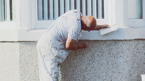 Side view of man relaxing on window