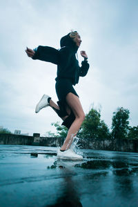 Low angle view of boy jumping against sky
