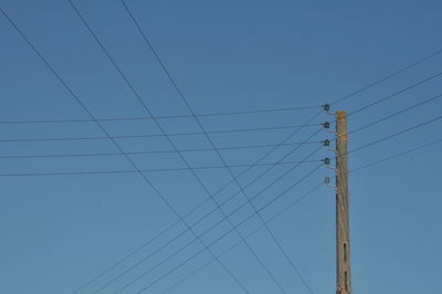 Low angle view of power lines against clear blue sky