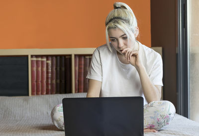 Young woman using laptop while sitting on sofa at home