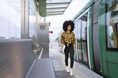 Woman with umbrella walking on railway station platform
