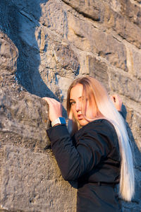 Portrait of young woman standing against wall