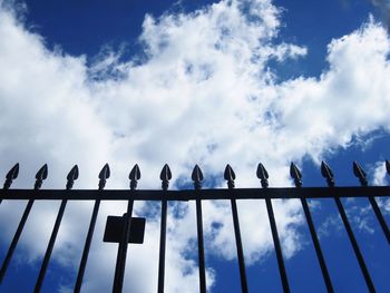 Low angle view of railing against cloudy blue sky