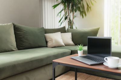 Midsection of laptop on sofa at home