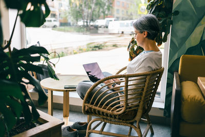 Side view of young woman sitting on chair in yard