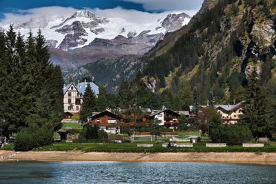 Houses and trees by lake against the monte rosa mountain, alps, italy