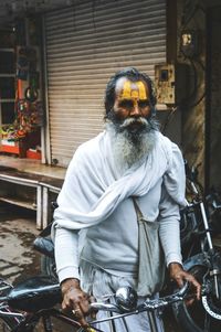 Portrait of senior man in traditional clothing with bicycle walking on street