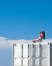 Woman standing by railing against blue sky