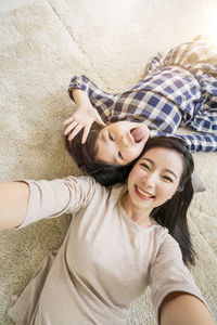 High angle portrait of mother and daughter lying on bed