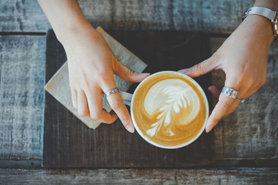 Midsection of woman holding coffee cup on table
