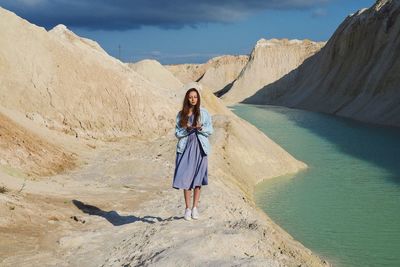 Woman standing by lake against mountains and sky