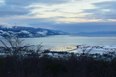 Scenic view of lake by snowcapped mountains against sky