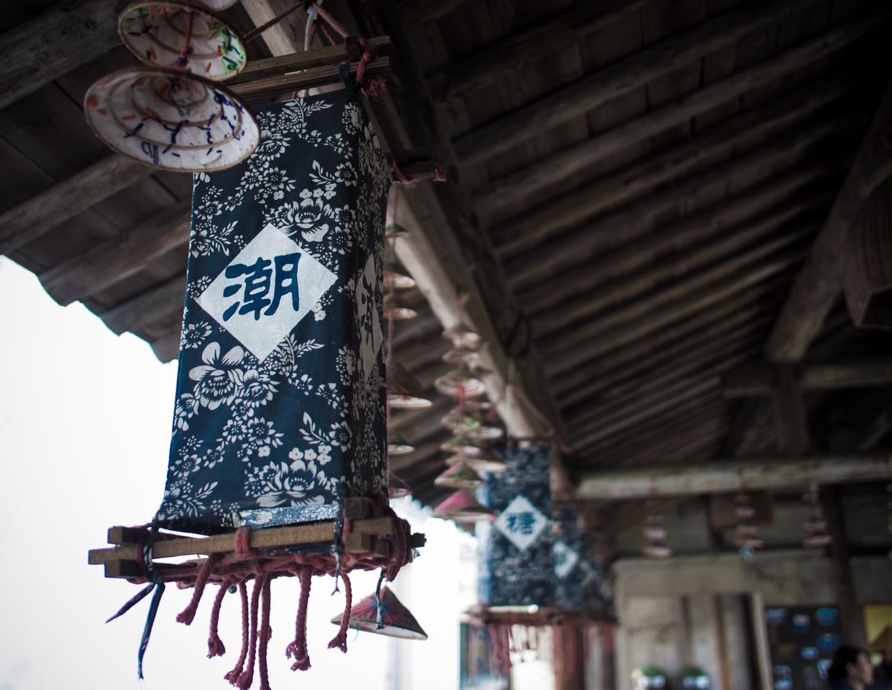 hanging, indoors, low angle view, built structure, decoration, lantern, architecture, lighting equipment, art and craft, no people, tradition, art, clothing, ceiling, wall - building feature, text, retail, cultures, illuminated, day