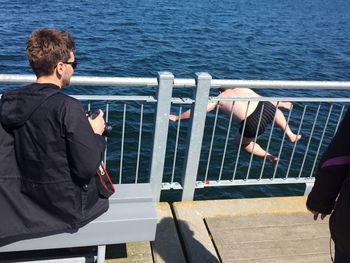 Men standing on railing by sea