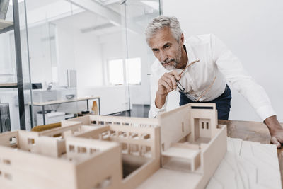 Mature businessman examining architectural model in office