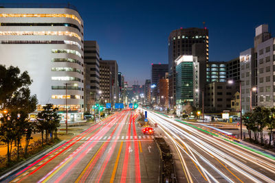 Light trails on city street amidst buildings at night