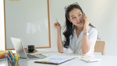 Young woman using phone while sitting on table