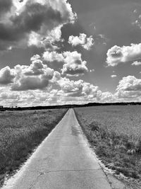 Road amidst field against sky