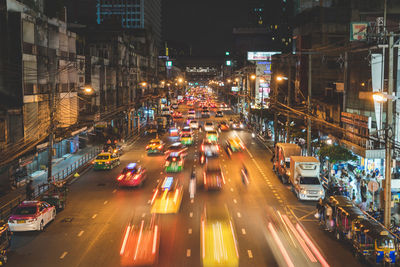 Blurred motion of cars on city street amidst buildings at night