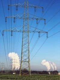 Low angle view of electricity pylon on field against sky