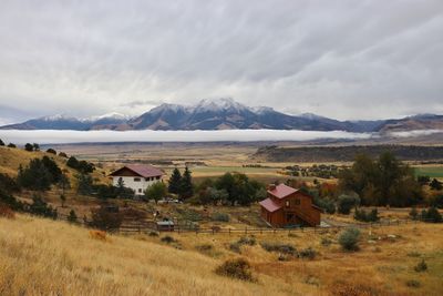 Houses on field by mountains against sky