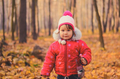 Beautiful girl in winter clothes with lollipop in the autumn park