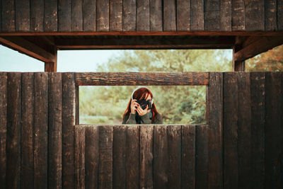 Woman sitting on wooden fence