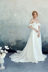 Portrait of beautiful bride standing by wall