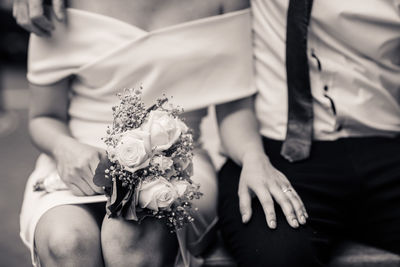 Midsection of newlywed couple sitting outdoors