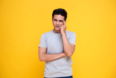 Portrait of smiling young man against yellow background