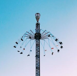 Low angle view of chain swing ride against clear blue sky