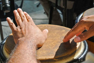 Cropped hands of drummer playing drums on street