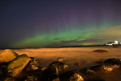 Scenic view of rocks at sea against sky at night