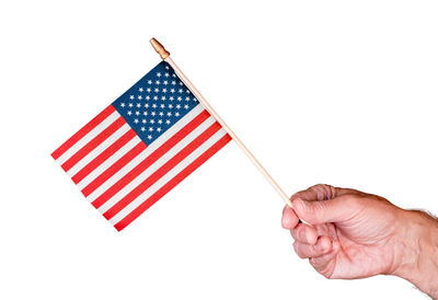 Close-up of hand holding flag against white background