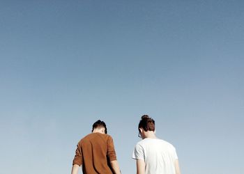 Low angle view of friends against clear sky