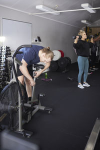 Fitness instructor adjusting exercise bike at health club