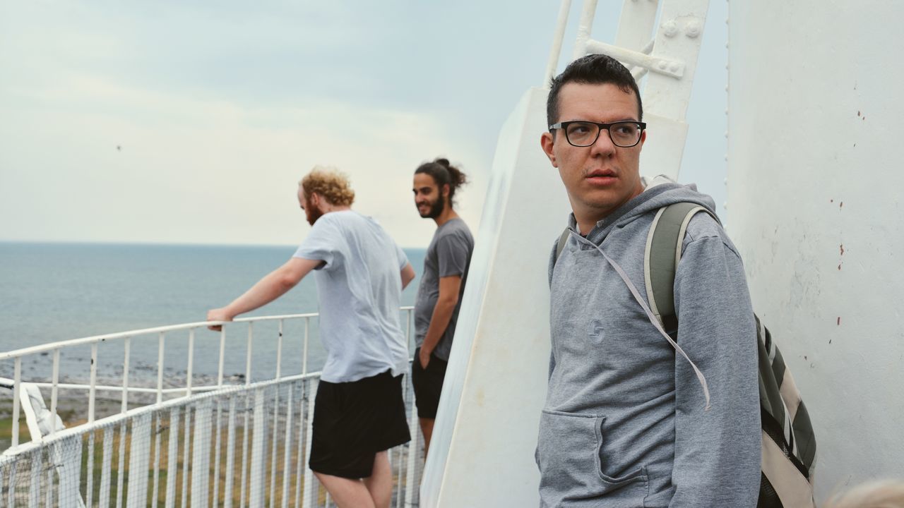 young men, real people, railing, young adult, standing, men, glasses, casual clothing, lifestyles, sky, people, water, adult, leisure activity, three quarter length, architecture, sea, young women, day, outdoors