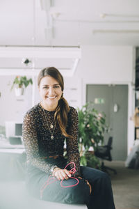 Portrait of smiling businesswoman sitting at table in creative office