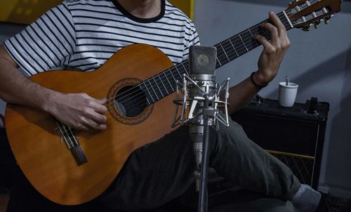 Midsection of man playing guitar