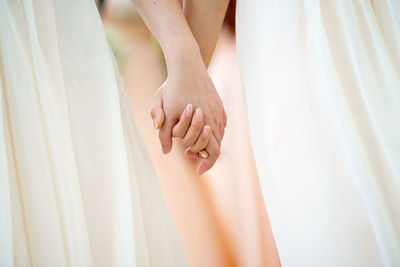 Close-up mid section of women holding hands