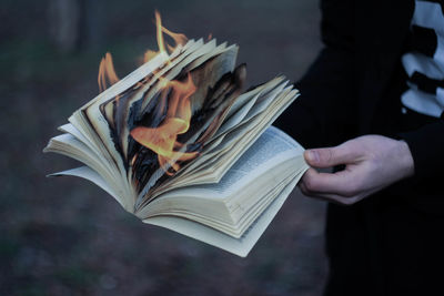 Midsection of person holding burning book