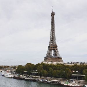 View of tower in city against cloudy sky