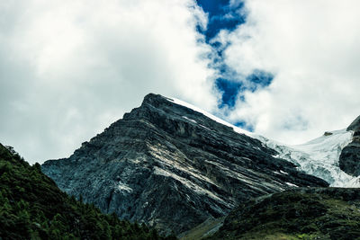 Low angle view of mountain range against cloudy sky