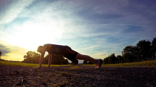 Full length of man exercising on road during sunset